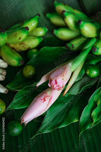 Asian food ingredient with bunga kantan or torch lily, calamansi, lemongrass, tumeric leaves and bananas on a banana leaf background.