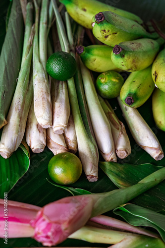 Asian food ingredient lemongrass, calamansi, tumeric leaves and bananas on a banana leaf background.
