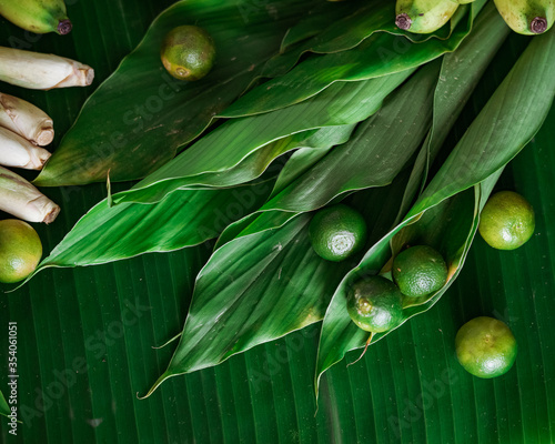 Asian food ingredients calamansi and tumeric leaves banana leaf background.