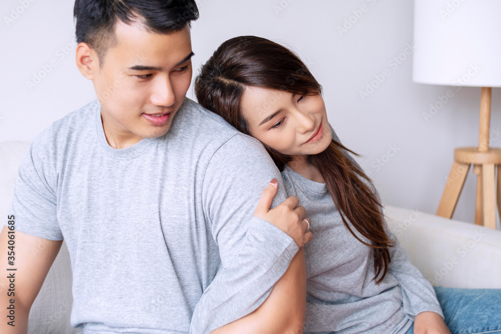 Cheerful smile young woman back to shoulder holding arm her boyfriend together while sitting relax in living room. Relationship togetherness couple love concept.