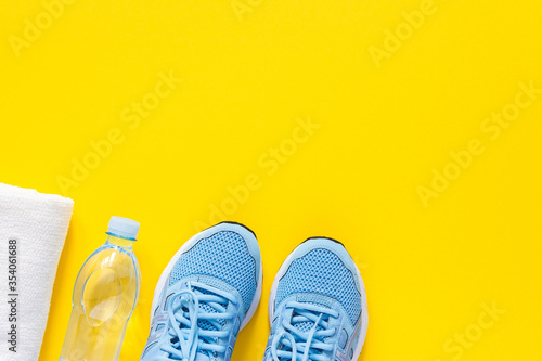 Blue sneakers and a towel with water on a yellow background, playing sports or fitness, top view, healthy sport lifestyle concept