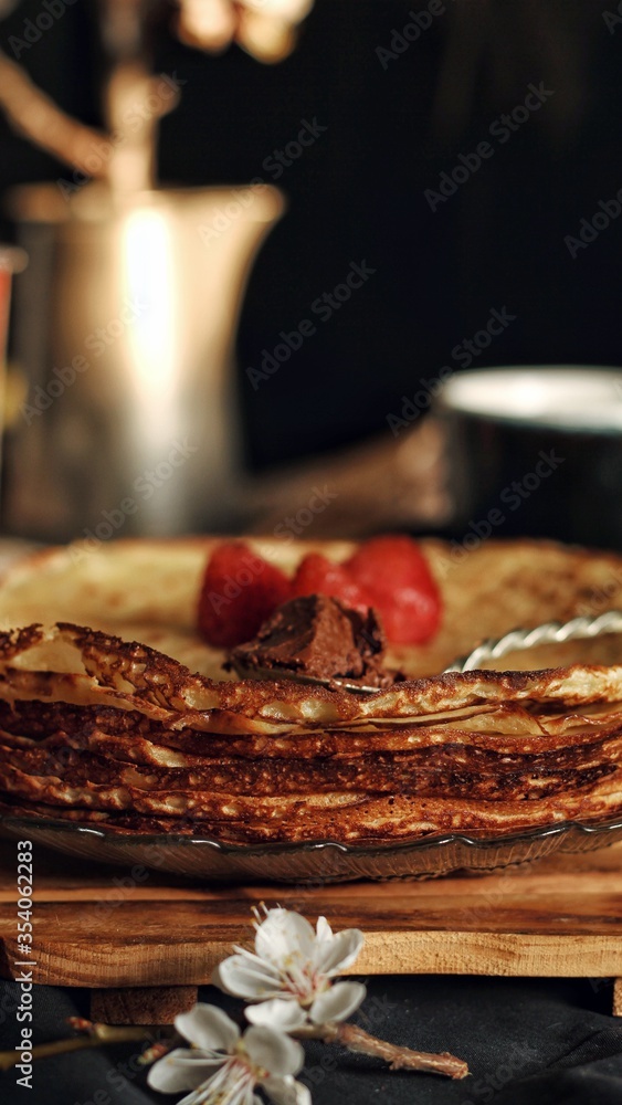 Thin crepes, pancakes or blinis on slate isolated on black background, tasty breakfest