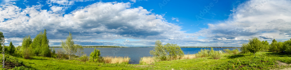 Summer landscape with lake, blue sky and clouds. Nature wilderness. Countryside outdoors, relaxation, space scenic. Beautiful pond, forest, green meadow with reflection in water. Panoramic views. Summer landscape with lake, blue sky and clouds. Nature wilderness. Countryside outdoors, relaxation, space scenic. Beautiful pond, forest, green meadow with reflection in water. Panoramic views.