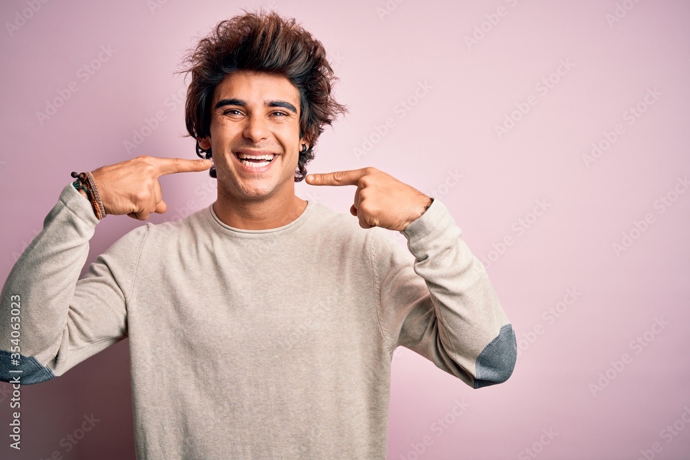 Young handsome man wearing casual t-shirt standing over isolated pink background smiling cheerful showing and pointing with fingers teeth and mouth. Dental health concept. Young handsome man wearing casual t-shirt standing over isolated pink background smiling cheerful showing and pointing with fingers teeth and mouth. Dental health concept.