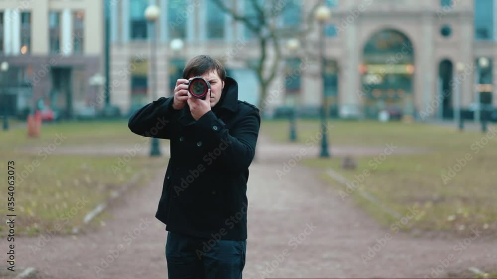 A male photographer in a black coat approaches the position and takes pictures from the camera. A male photographer in a black coat approaches the position and takes pictures from the camera.
