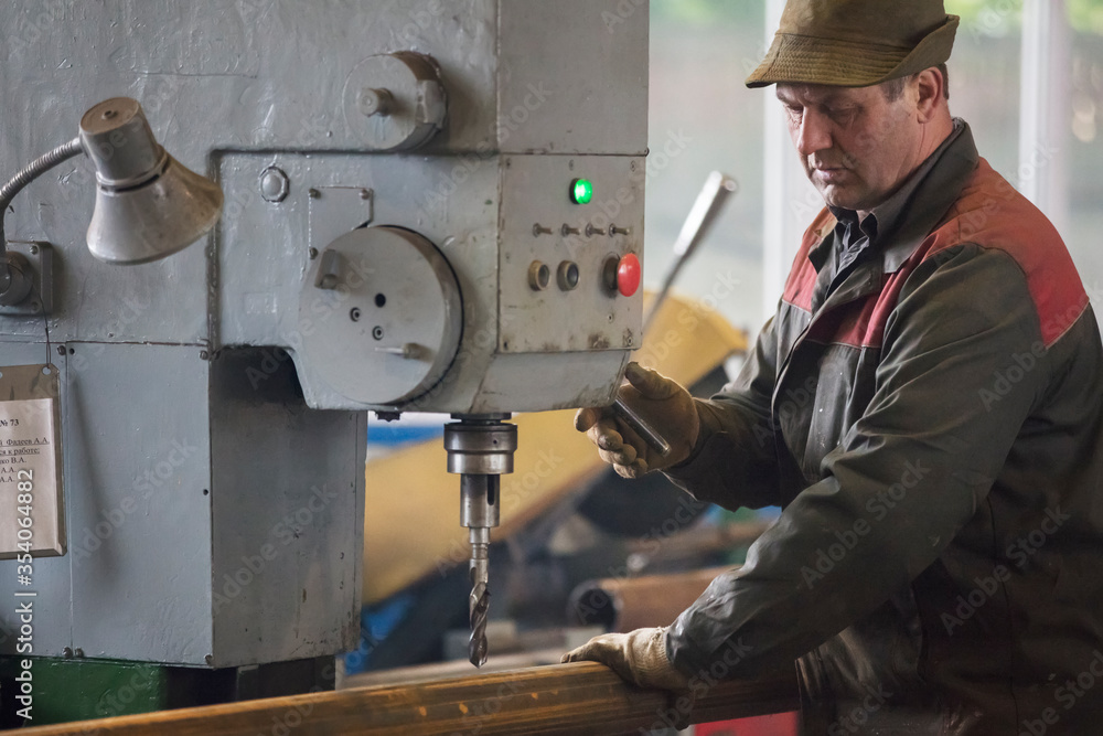Worker at the current machine in the workshop. Worker at the current machine in the workshop.