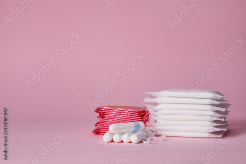 stack of menstrual sanitary cotton pads and tampon on pink background. Feminine hygiene products. copy space. photo