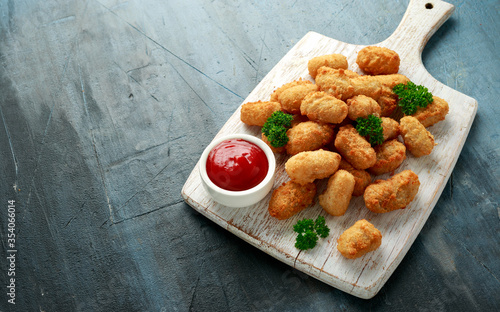 Crispy Battered scampi nuggets with ketchup on white wooden board photo