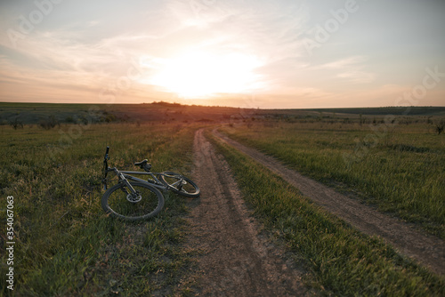 Mountain bike lies on the ground during beautiful sunset on the horizon. Mountain bicycle