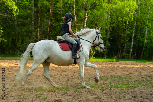Woman riding horse through field.