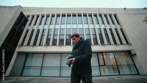 Wallpaper Mural A photographer in a black coat standing on the street makes frames from the camera while shooting in different directions. Torontodigital.ca
