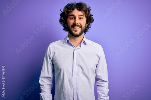 Young handsome business man with beard wearing shirt standing over purple background with a happy and cool smile on face. Lucky person.