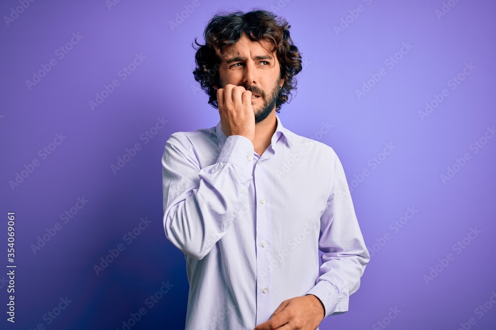Young handsome business man with beard wearing shirt standing over purple background looking stressed and nervous with hands on mouth biting nails. Anxiety problem. Young handsome business man with beard wearing shirt standing over purple background looking stressed and nervous with hands on mouth biting nails. Anxiety problem.