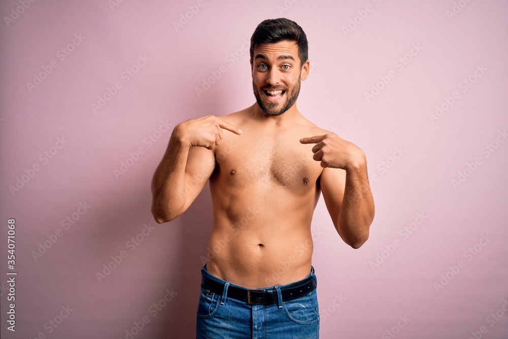 Young handsome strong man with beard shirtless standing over isolated pink background looking confident with smile on face, pointing oneself with fingers proud and happy.