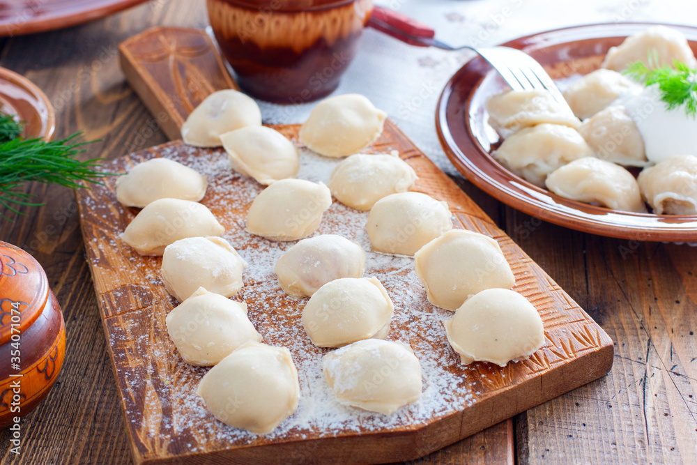 Raw homemade dumplings on a wooden board, selective focus Raw homemade dumplings on a wooden board, selective focus