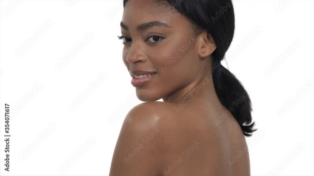 Profile view of seductive African woman with naked shoulders gently touching her lips and posing to the camera. Isolated, on white background Profile view of seductive African woman with naked shoulders gently touching her lips and posing to the camera. Isolated, on white background