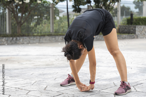 Young female workout before fitness training session at the park. Healthy young woman warming up outdoors.