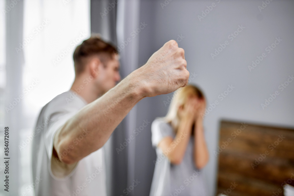 domestic violence, man raises his hand to wife, going to beat and humiliate her at home, woman afraid of him. abusive relationships concept. close-up photo of male fist domestic violence, man raises his hand to wife, going to beat and humiliate her at home, woman afraid of him. abusive relationships concept. close-up photo of male fist