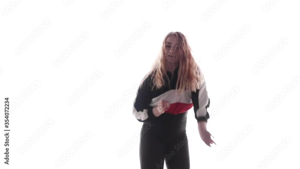 Attractive female modern style dancer performing in the studio. Hip hop street dance on a stage in front of the spotlight. Isolated. Medium long shot. Slow motion. Contemporary choreography Attractive female modern style dancer performing in the studio. Hip hop street dance on a stage in front of the spotlight. Isolated. Medium long shot. Slow motion. Contemporary choreography
