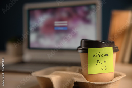 Back to Work Concept. Closeup of Welcome Note on Takeaway Coffee Cup in Office Desk. Message from a Colleague or Boss photo