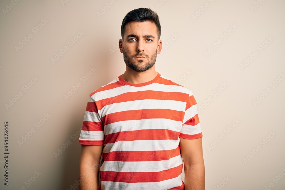 Young handsome man wearing casual striped t-shirt standing over isolated white background Relaxed with serious expression on face. Simple and natural looking at the camera. Young handsome man wearing casual striped t-shirt standing over isolated white background Relaxed with serious expression on face. Simple and natural looking at the camera.