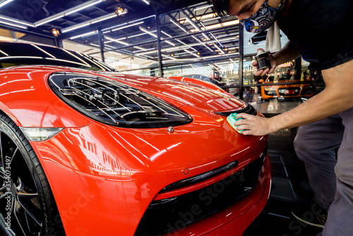 Car service worker applying nano coating on a car detail © romaset