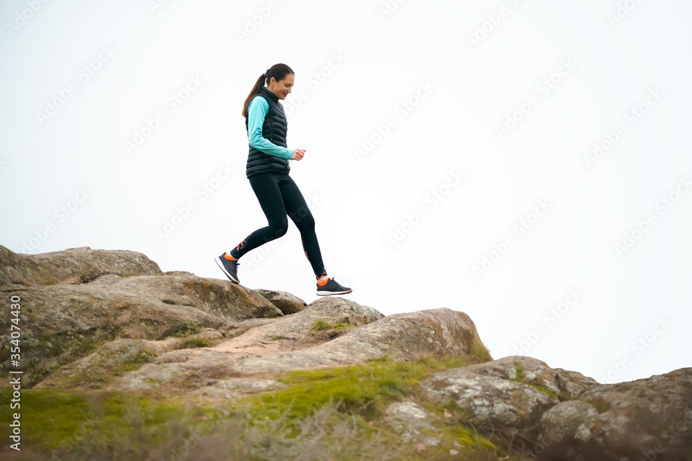 Beautiful Woman Running on the Mountain Trail at Cold Autumn Evening. Sport and Active Lifestyle.