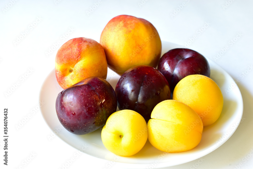 Ripe and juicy peaches and apricots on a white plate Ripe and juicy peaches and apricots on a white plate