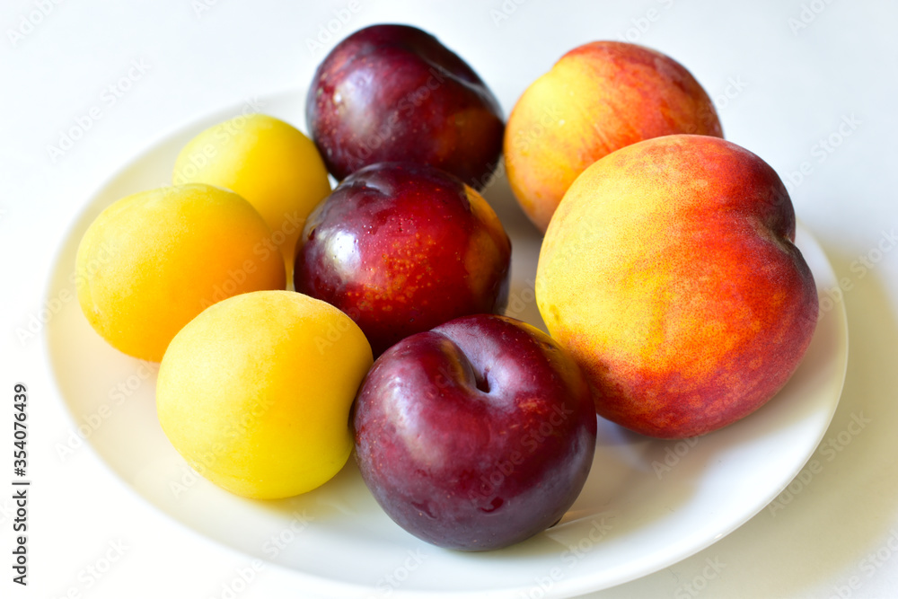 Ripe and juicy peaches and apricots on a white plate
