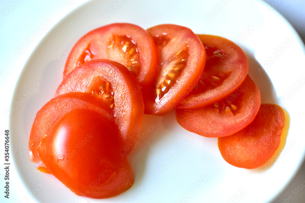 Ripe and juicy tomatoes sliced on a white plate Ripe and juicy tomatoes sliced on a white plate