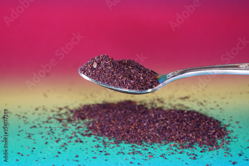 Sumac spice powder with macro lens photographed against colorful gradient in studio