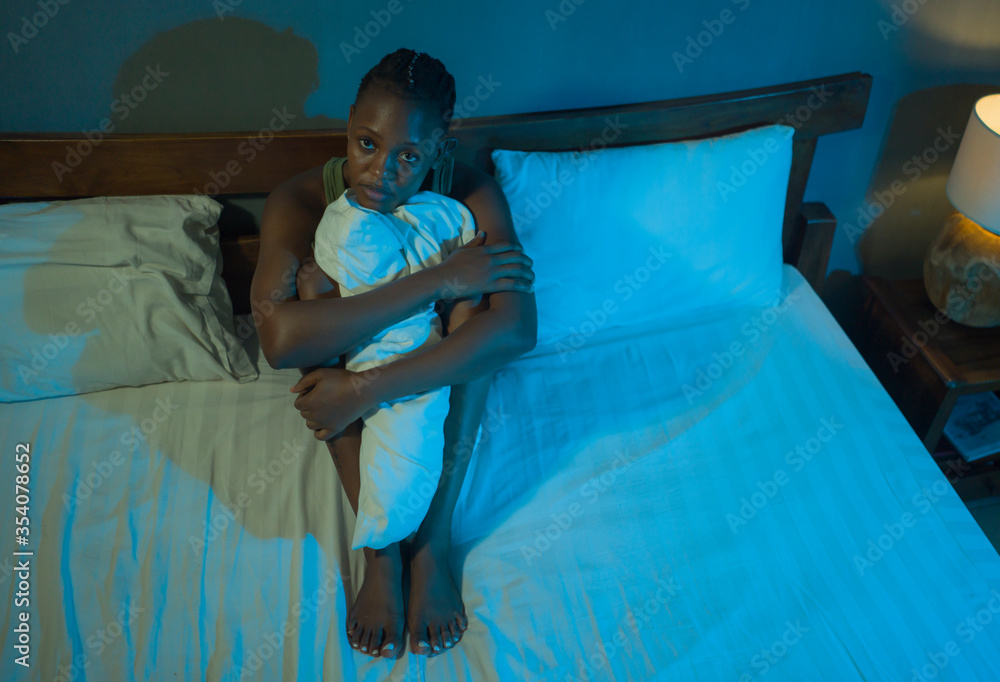 Obraz premium young sad and depressed black African American woman sitting on bed at home sleepless at night feeling overwhelmed suffering depression problem thoughtful