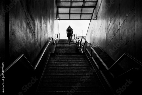 Pessoa solitária sobe escadaria de saída do metrô