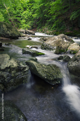 Fast moving water cascades over boulders in a cool river in springtime Virginia in the Blue Ridge Mountains