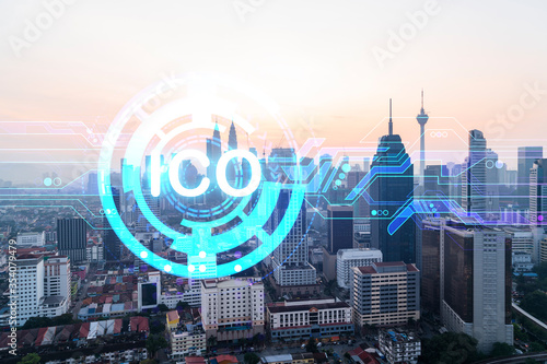Hologram of glowing ICO icon, sunset panoramic city view of Kuala Lumpur. KL is the startup incubator of cryptocurrency projects in Malaysia, Asia. The concept of affordable opportunities in new era.