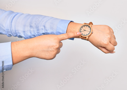 Hand of caucasian young businesswoman wearing wristwatch. Pointing with finger to watch over isolated white background