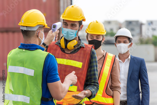 Workers with protective mask, Engineer worker waring surgical mask checking body temperature using infrared digital thermometer check temperature before into work place,