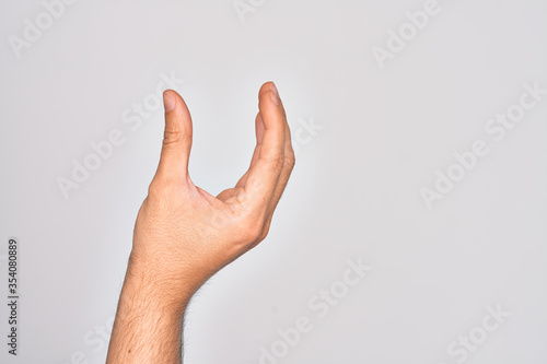 Hand of caucasian young man showing fingers over isolated white background picking and taking invisible thing  holding object with fingers showing space