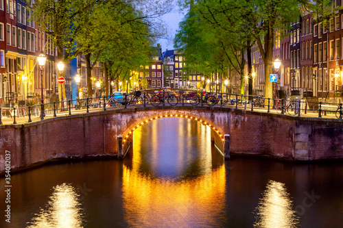 Amsterdam canal with typical dutch houses during twilight blue hour in Holland, Netherlands.