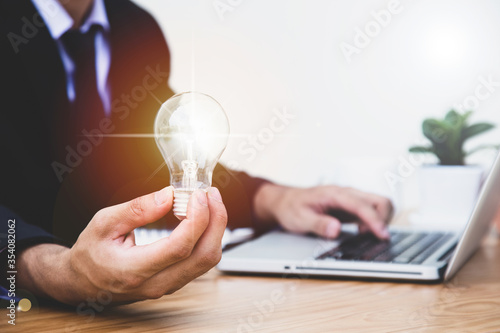 Business man holding light bulb. concept saving energy and money.