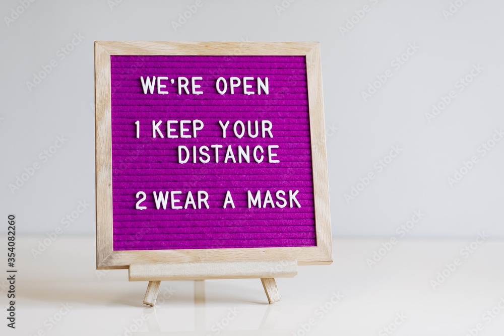 We're open, keep your distance, wear a mask text on purple letter board near the notebook. Business concept. Service, restaurant, shop and cafe. Reopening of the place after the quarantine covid-19.