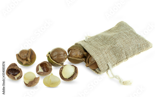 Group of peeled and unpeeled macadamia nuts in sack bag at white background