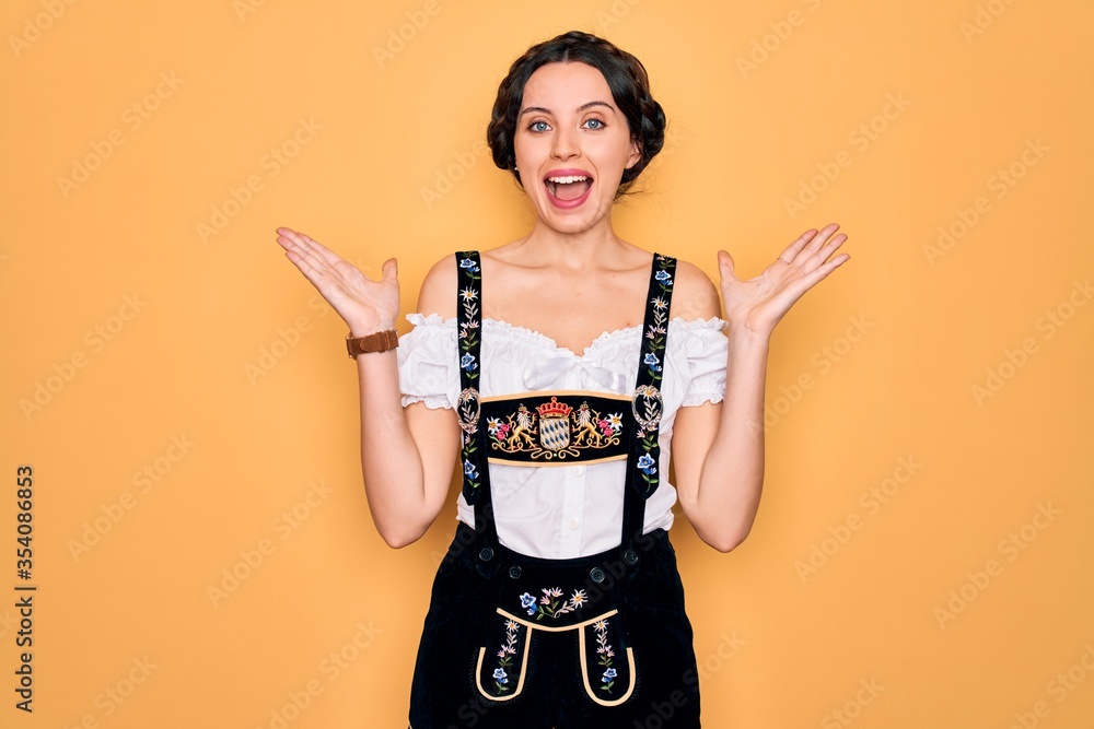 Young beautiful german woman with blue eyes wearing traditional octoberfest dress celebrating crazy and amazed for success with arms raised and open eyes screaming excited. Winner concept Young beautiful german woman with blue eyes wearing traditional octoberfest dress celebrating crazy and amazed for success with arms raised and open eyes screaming excited. Winner concept