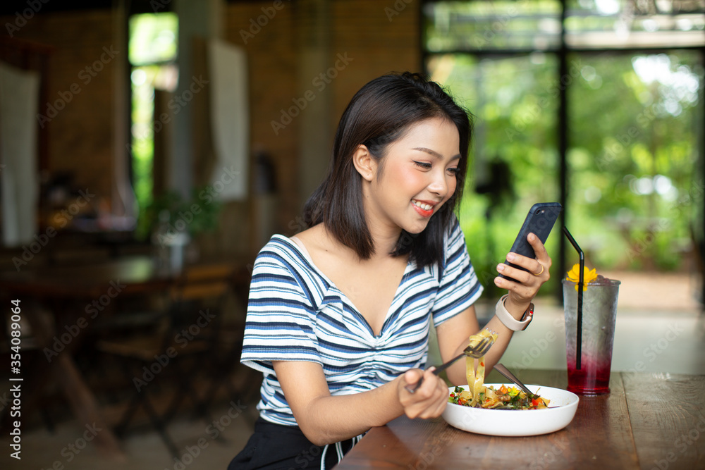 Woman eating delicious pasta and using smart phone in restaurant