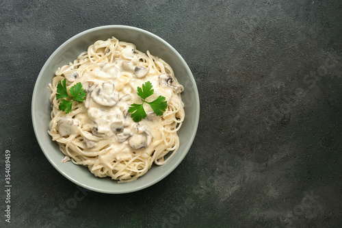 Fotografia Spaghetti pasta with creamy mushroom sauce on a dark painted background