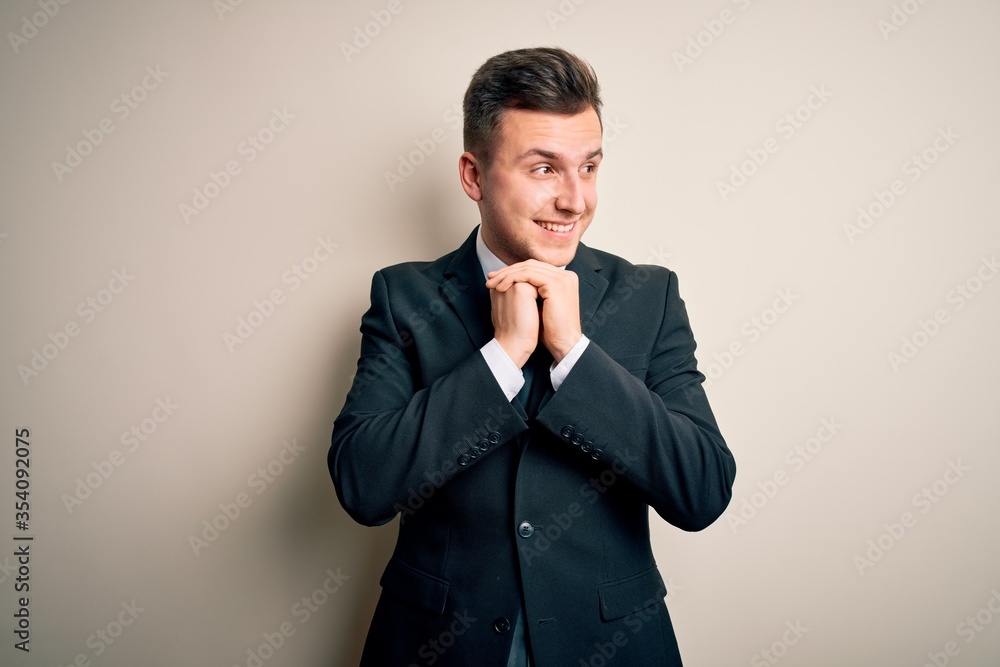 Young handsome business man wearing elegant suit and tie over isolated background laughing nervous and excited with hands on chin looking to the side