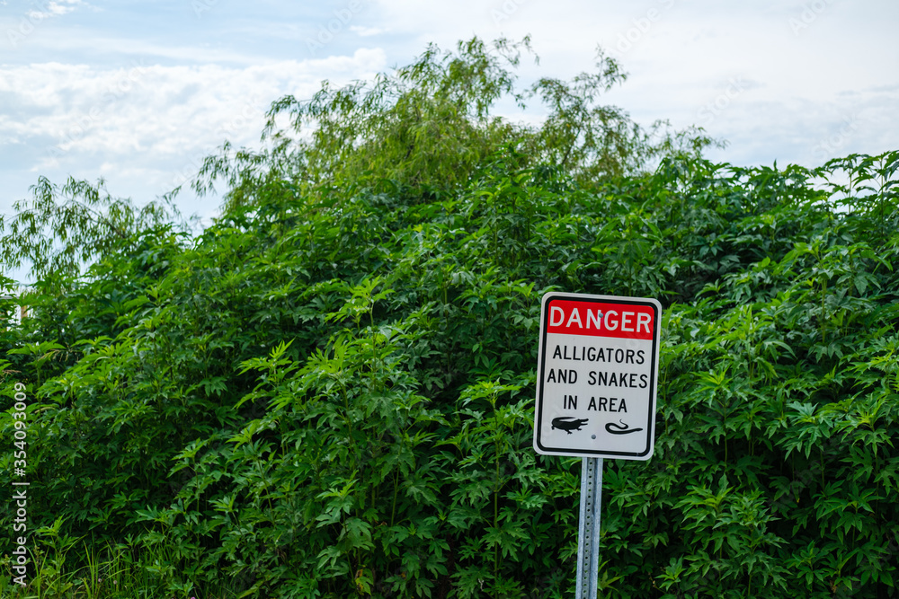 Danger alligators and snakes sign on Lake Pontchartrain in Bucktown Marsh, Metairie, Louisiana, USA