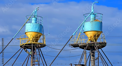 large color grain bin bunker (dispenser and dryer) behind the wires at elevator on blue sky in sunny day, modern technology diversity