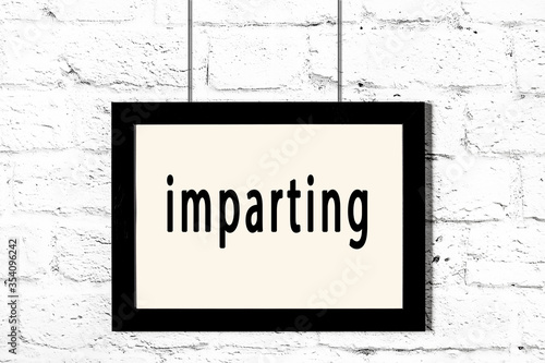 Foto Black frame hanging on white brick wall with inscription imparting