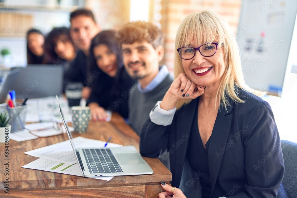 Group of business workers sitting in line with smile on face. Looking at the camera, middle age woman smiling at the office Group of business workers sitting in line with smile on face. Looking at the camera, middle age woman smiling at the office